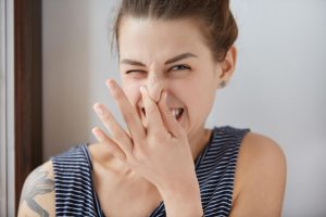 woman indicating a bad smell that is likely a sign of plumbing problems